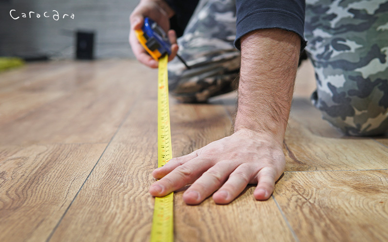Person measuring a room for furniture placement and interior planning.